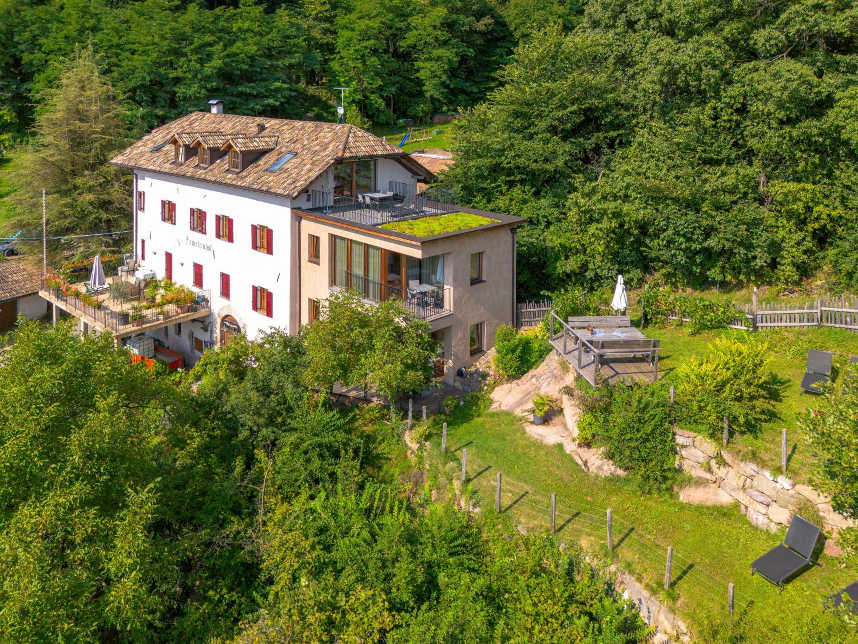 Luftaufnahme des Firmeleinhofs mit moderner Glasfront und Garten
